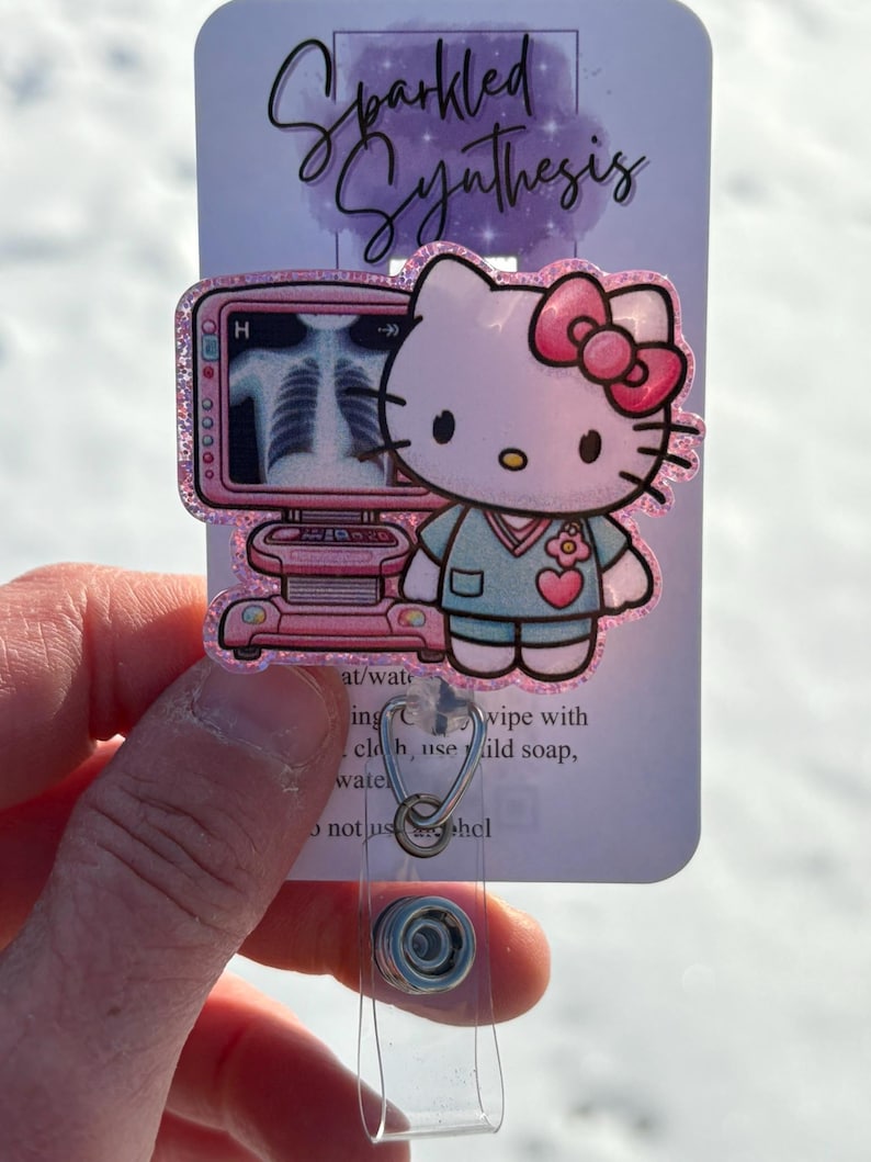 May include: Pink Hello Kitty character wearing a light blue scrub top with a pink flower on the pocket. The character is holding a pink and white medical device with an x-ray image on the screen. The text "Sparkled Synthesis" is at the top of the image.