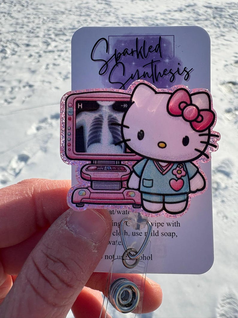 May include: A pink Hello Kitty character wearing a blue scrub top and a pink bow. The character is holding a pink medical device with a screen displaying a black and white image of a chest x-ray. The image is on a white background with the text "Sparkled Synthesis" in black.