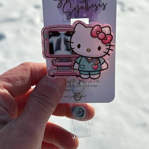 May include: Pink Hello Kitty themed badge holder with a glittery finish. The badge holder features Hello Kitty dressed as a doctor with a pink ultrasound machine. The text "Sparkled Synthesis" is printed on the back of the badge holder.
