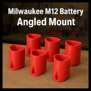 May include: Six red, angled mounts for Milwaukee M12 batteries are arranged on a wooden surface. The mounts are cylindrical with a curved top and a small opening on the side. The text "Milwaukee M12 Battery Angled Mount" is displayed at the top.