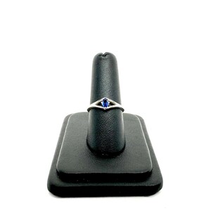 May include: A silver ring with a blue gemstone set in a delicate, open-work design.