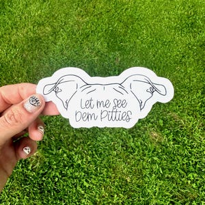 May include: White sticker with a black line drawing of a dog's head and the text "Let me see dem Pitties".