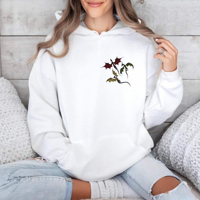May include: White hoodie with a graphic of three dragons flying in a formation. The dragons are red, green, and black.