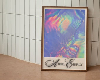 Pode incluir: Uma impressão emoldurada com um design holográfico iridescente em tons de azul, rosa e verde. A impressão tem o texto "Angel Energy" em uma fonte cursiva.