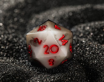 May include: A white twenty-sided die with red numbers. The die is sitting on a black surface.