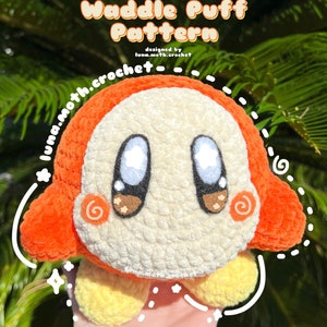 Könnte beinhalten: Ein gehäkeltes Waddle Dee Plüschtier in Orange, Weiß und Gelb. Das Spielzeug hat einen runden Körper, kleine Arme und Beine. Das Spielzeug wurde von luna.moth.crochet entworfen.