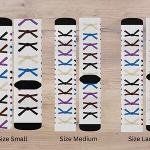 May include: Three pairs of white socks with a pattern of different colored martial arts belts. The socks are shown in three sizes: small, medium, and large.