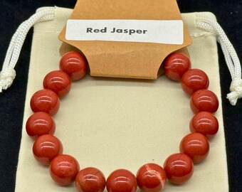Red jasper beaded stretch bracelet on a light surface