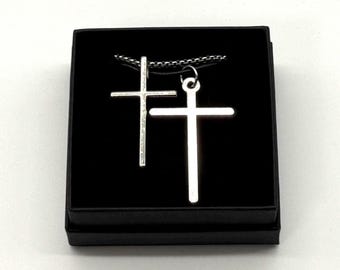 Two cross crucifix pendant necklaces displayed together with a gift box