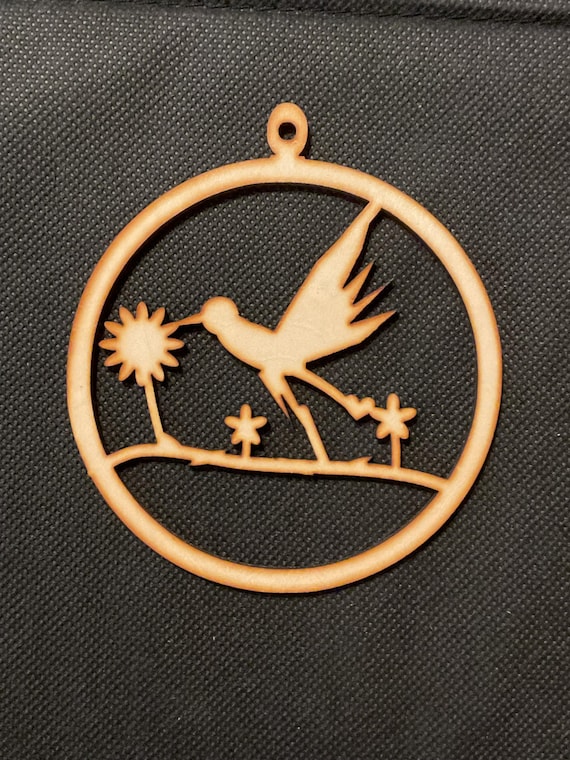 Three unfinished laser-cut basswood ornaments with hummingbird and wildflower cutouts