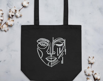 Eco cotton tote bag printed with an abstract hand-drawn One-Eyed Muse face design by Robert Anthony