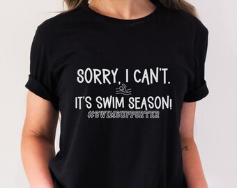 May include: A black t-shirt with white text that reads "Sorry, I can't. It's swim season! #swimsupporter".