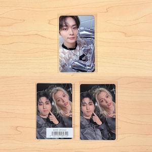 May include: Three photo cards on a wooden surface. The top card features a person holding a silver balloon. The bottom cards show two people. One card has the text "ZZZZ-203322" and a barcode. The cards are in clear plastic sleeves.