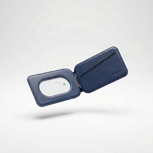 Peut inclure: Portefeuille en cuir bleu marine ouvert, avec un int&eacute;rieur blanc et une petite lumi&egrave;re verte. Le portefeuille est ouvert, r&eacute;v&eacute;lant une fente pour carte et une petite ouverture rectangulaire. Le portefeuille est en cuir lisse.