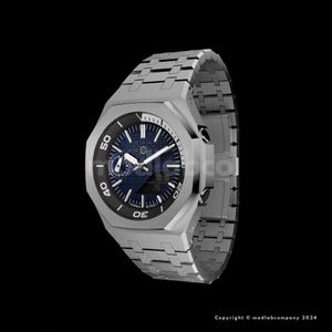 May include: A silver-toned wristwatch with a dark blue face and a matching metal band. The watch features a black bezel with white numerals and markers. The watch face displays the time and other information.