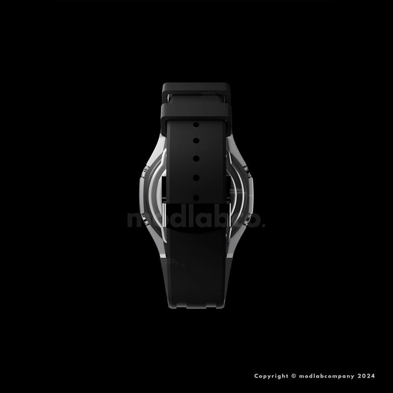 May include: A black and silver wristwatch with a black band. The watch face is visible, and the band is secured with a buckle. The watch has the text "modlab" on the face. The background is black.