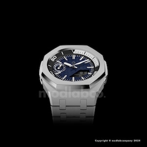 May include: A silver-toned wristwatch with a blue face and a textured pattern. The watch has a geometric design with a black bezel and a silver band. The watch face displays the time and other indicators.