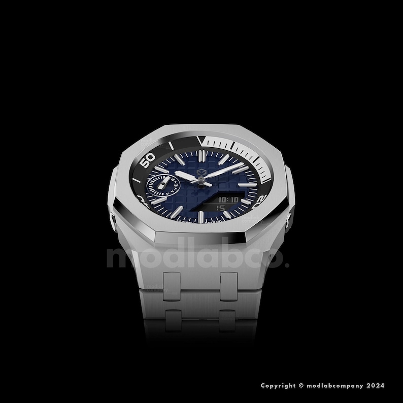 May include: A silver-toned wristwatch with a blue face and a textured pattern. The watch has a geometric design with a black bezel and a silver band. The watch face displays the time and other indicators.