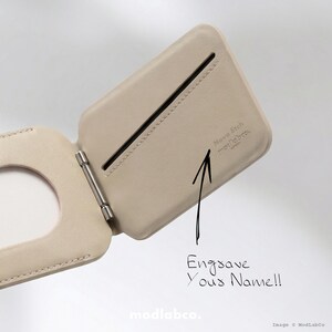 Puede incluir: Cartera de cuero beige claro abierta, con una bisagra plateada. La cartera tiene una ranura y el texto "Engrave Your Name!!" est&aacute; escrito en la imagen. La marca "modlabco." es visible en la parte inferior.