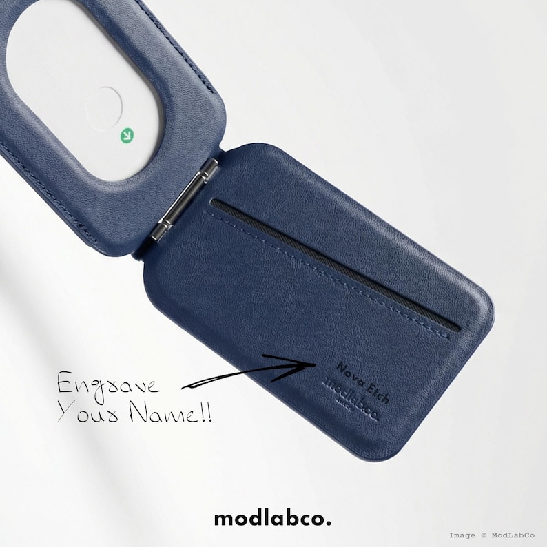 Peut inclure: Un &eacute;tui de t&eacute;l&eacute;phone en cuir bleu marine, ouvert pour r&eacute;v&eacute;ler une fente pour carte et un int&eacute;rieur blanc. L'&eacute;tui est articul&eacute; et comporte le texte "Engrave Your Name!!" et "Nova Etch modlabco."