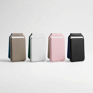 Puede incluir: Cuatro tarjeteros de cuero para tel&eacute;fono en fila. Los colores son topo, blanco, rosa y negro. Cada tarjetero tiene una ranura para tarjetas y un panel trasero de color contrastante. Los tarjeteros est&aacute;n de pie sobre un fondo blanco.