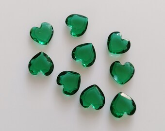 Op de afbeelding: Tien groene hartvormige glazen edelstenen op een witte achtergrond.