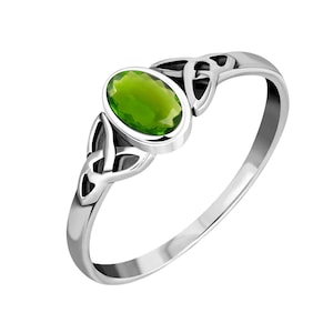Puede incluir: Un anillo de plata con una piedra ovalada verde engastada en un diseño de nudo celta.