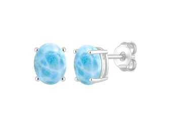 May include: A pair of oval-shaped larimar stud earrings. The earrings feature a light blue stone with white marbling, set in a silver metal frame. The earring posts have butterfly clasps.