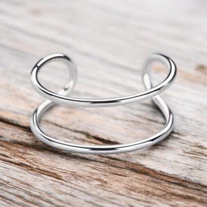 May include: A silver double-band bangle bracelet with a simple, modern design.
