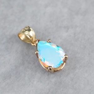 May include: A gold pendant featuring a pear-shaped iridescent blue gemstone. The pendant has a simple design with a bail at the top.