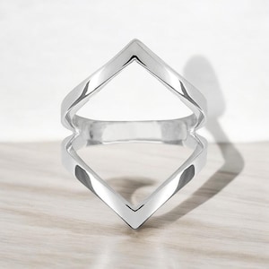 以下が含まれることがあります： ダイヤモンド型の幾何学模様が施されたシルバーリング。リングは片側が開いており、ユニークでモダンなルックを生み出しています。