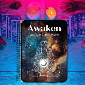 May include: A black and white planner with a spiral binding. The cover features a galaxy background with a white outline of a woman meditating with a crescent moon in her hands. The text "Awaken Your Inner Goddess Planner" is printed in white on the cover.