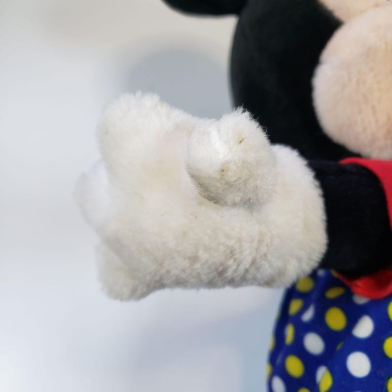 K&ouml;nnte beinhalten: Nahaufnahme eines wei&szlig;en Pl&uuml;sch-Mickey-Mouse-Handschuhs mit schwarzen N&auml;hten. Der Handschuh ist aus weichem, flauschigem Material und hat ein leicht abgenutztes Aussehen.