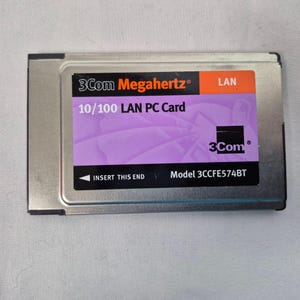 May include: A silver 3Com Megahertz 10/100 LAN PC Card. The card has a purple label with white text and the 3Com logo. The label also includes the text "INSERT THIS END" and the model number 3CCFE574BT.