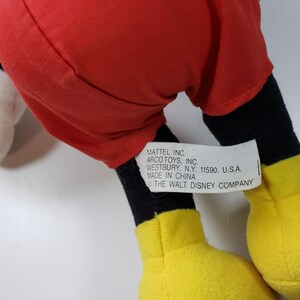 May include: A red and black plush Mickey Mouse toy with yellow shoes. The tag on the toy reads "MATTEL INC. ARCO TOYS, INC. WESTBURY, N.Y. 11590, U.S.A. MADE IN CHINA &copy; THE WALT DISNEY COMPANY"