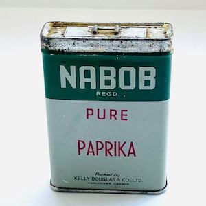 Op de afbeelding: Een vintage groene metalen blik met een wit etiket waarop "NABOB REGD. PURE PAPRIKA" en "Packed by KELLY DOUGLAS & CO. LTD. VANCOUVER, CANADA" staat.