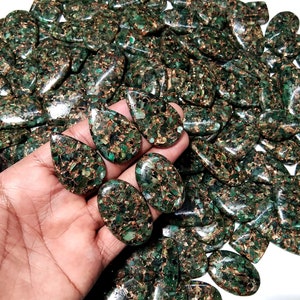May include: A large collection of green and gold teardrop-shaped cabochons. The stones are made of a green material with gold flecks throughout.