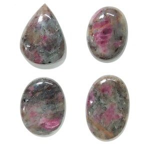 May include: Four polished gemstones in various shapes. The stones feature a mix of colours, including pink, grey, and brown, with a glossy finish. One stone is teardrop-shaped, while the others are oval.