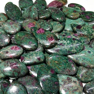 May include: A collection of green and pink ruby zoisite tumbled stones. The stones are smooth and polished, with a variety of shapes and sizes.  The stones are a beautiful shade of green with pink accents.