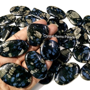 Op de afbeelding: Een verzameling gepolijste edelstenen met een donkerblauw, grijs en wit gevlekt patroon. De stenen variëren in vorm, waaronder ovaal, rond en rechthoekig. De edelstenen zijn glad en reflecterend, met een glanzende afwerking. De afbeelding is goed belicht.