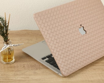 May include: A light pink laptop case with a woven pattern and an Apple logo. The case is on top of a laptop with a silver keyboard.