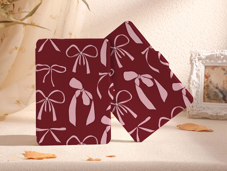 May include: Two burgundy book covers featuring a pink bow pattern. The covers are made from a soft, durable material and are ideal for protecting your favourite books.