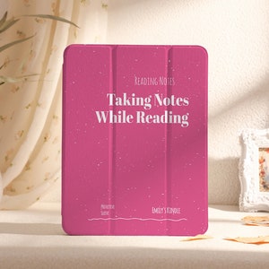 May include: A pink Kindle cover with the text "Reading Notes Taking Notes While Reading" and "Emily's Kindle" printed on it.