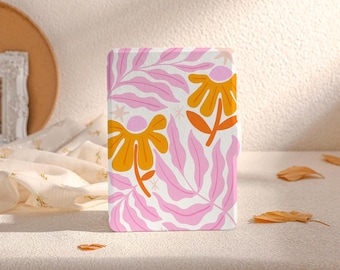 以下が含まれることがあります： オレンジと黄色の花が咲いた、ピンクと白の携帯電話ケース。花はレトロなスタイルです。