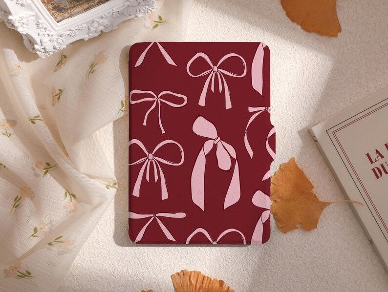May include: A burgundy red phone case with a repeating pattern of pink bows.