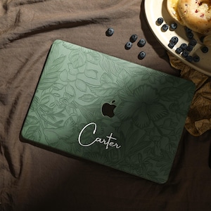 May include: A green laptop skin with a floral design and the name "Carter" written in white script.