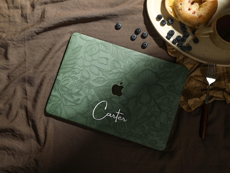 May include: A green laptop skin with a floral design and the name "Carter" written in white script.