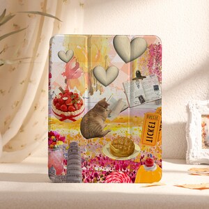 May include: A colourful iPad case featuring a collage of images including a cat, a cake, a heart, a book, a ticket, and a tower. The background is a watercolour wash of pink, yellow, and orange.