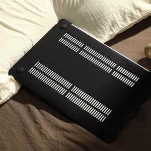 May include: Black laptop case with a textured, vented design. The case is made of hard plastic and has a smooth, matte finish.