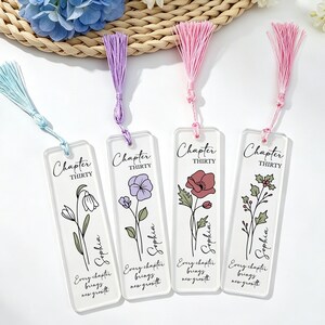 Könnte beinhalten: Vier transparente Acryl-Lesezeichen mit farbigen Quasten. Jedes Lesezeichen zeigt ein Blumendesign, die Worte "Chapter Thirty" und den Namen "Sophia". Der Satz "Every chapter brings new growth" ist ebenfalls aufgedruckt.